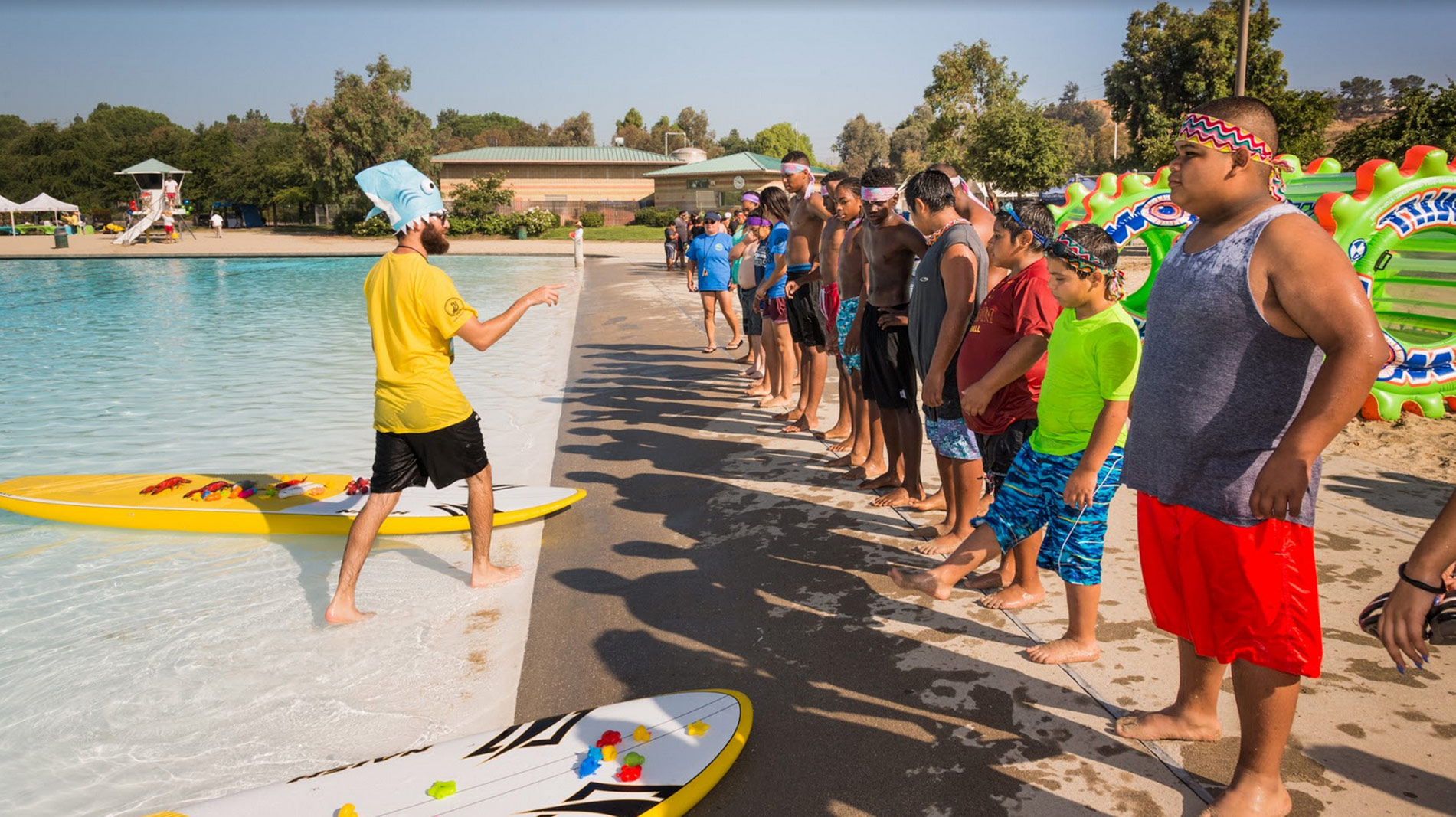 children lined up to receive paddleboarding instructions